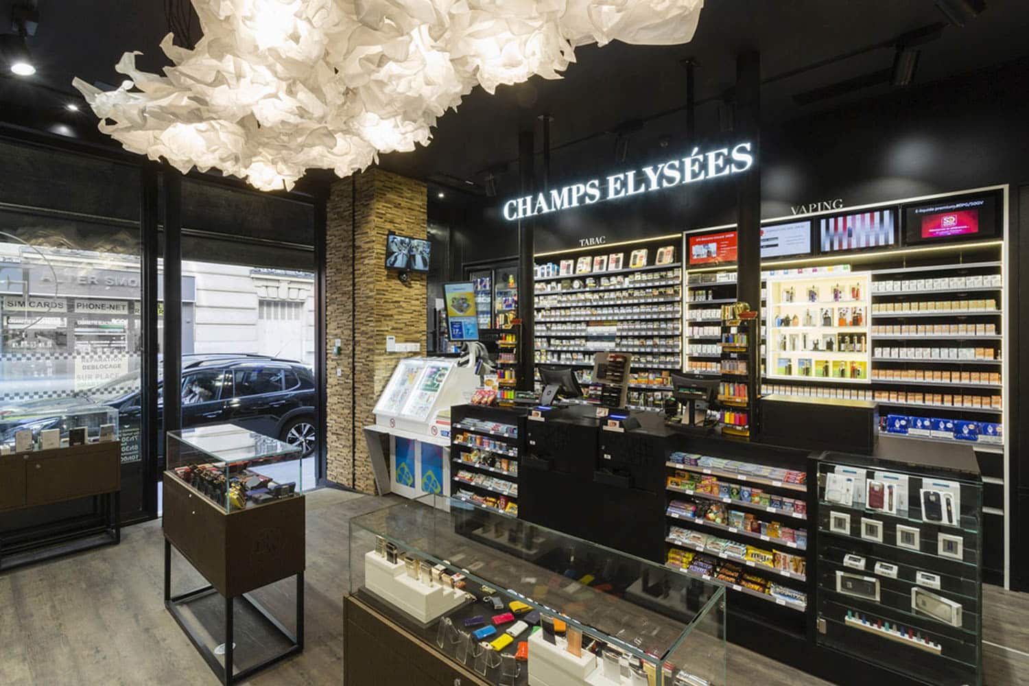 Design Transformation bureau de tabac Civette Paris La Civette Elysée Washington, un bureau de tabac de 30 m² près des Champs-Élysées, a repensé son offre pour redevenir un acteur clé du quartier. L’espace a été optimisé pour diversifier les produits, attirant à la fois les locaux et les touristes. Un parcours client fluide, avec une disposition soignée des rayons et un merchandising adapté, a remplacé la vente assistée par le libre-service, encourageant ainsi une plus longue présence en boutique. Travaux Agencement bureau de tabac